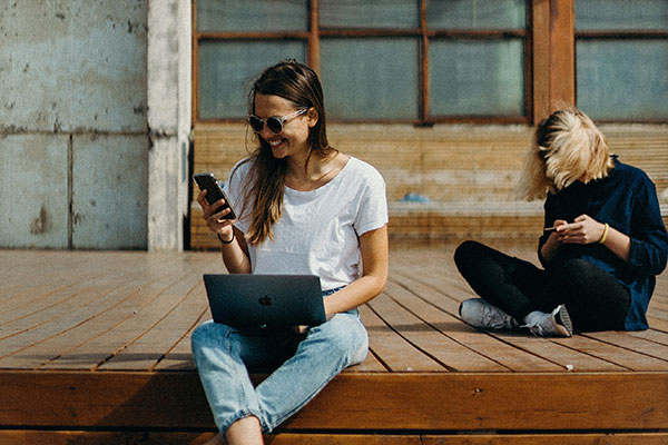 woman with laptop checking her phone